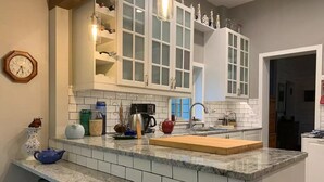 A kitchen with white cabinets, a granite countertop, a clock, and various kitchen appliances. - History and Romance abound in this restored home & cabin in cozy Evergreen (Evergreen)