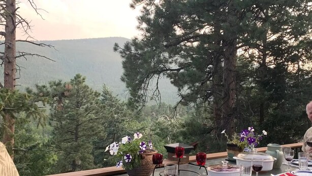An outdoor dining table set with plates, cutlery, and glasses, surrounded by potted plants and overlooking a mountainous landscape. - History and Romance abound in this restored home & cabin in cozy Evergreen (Evergreen)