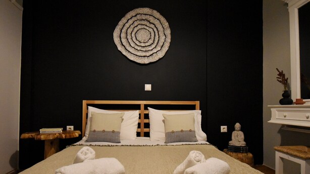 A neatly made bed with white linens and two rolled towels on the bed. - Seven Seconds Away (Athens)