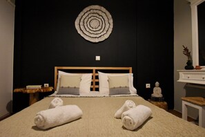 A hotel room with a bed, two nightstands, a wall-mounted circular decoration, and a statue. - Seven Seconds Away (Athens)