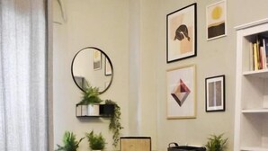A modern living room with a round table, two chairs, a bookshelf, and decorative items on the wall. - Seven Seconds Away (Athens)