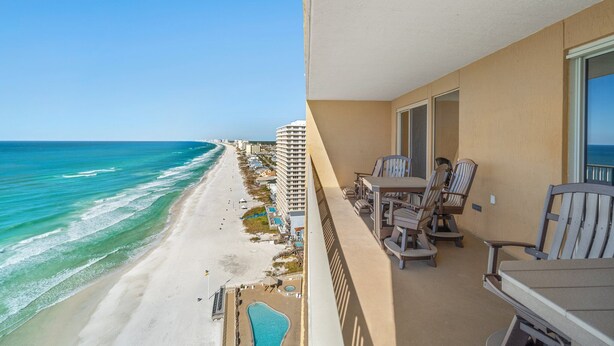 A balcony with a view of a beach and ocean, featuring outdoor furniture and a pool. - Tropical condo - pool, hot tub and beach access (Panama City Beach)