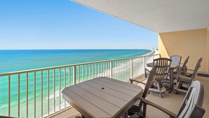 A balcony with a view of the ocean, a table, and several chairs. - Tropical condo - pool, hot tub and beach access (Panama City Beach)