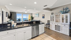 A kitchen with a large island, a dishwasher, and a view to the outside.
