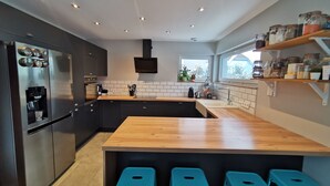 Una cocina moderna con una isla central, electrodomésticos integrados y un ventanal con vistas a zonas verdes.