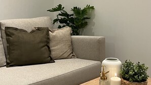Un salon moderne avec un canapé gris, une table basse en bois, une plante en pot et des objets décoratifs.