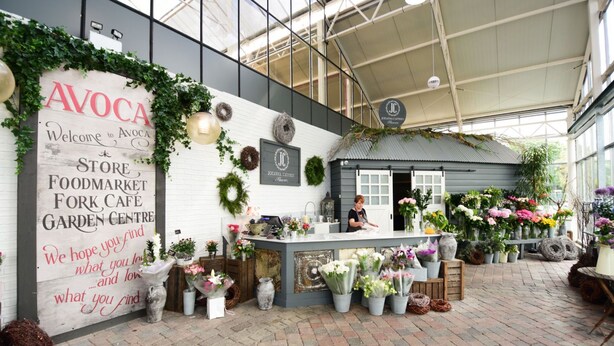 Un marché couvert avec une enseigne blanche indiquant les noms suivants : Avoca Store Foodmarket, Fork Cafe et Garden Centre.