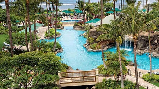 Ein Resort mit einem zentralen Pool, Palmen und Blick auf den Ozean.