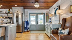 A kitchen with a stainless steel refrigerator, wooden cabinets, and a wooden floor. - A Rare Nautical Historic Gem! Steps to the Ocean! Grocery Next Door! (Panama City Beach)