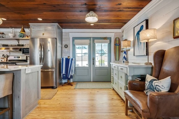 A kitchen with a stainless steel refrigerator, wooden cabinets, and a wooden floor.