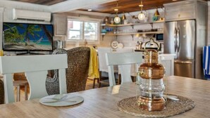 A modern kitchen with a large island, stainless steel appliances, and a dining area with a wooden table and chairs. - A Rare Nautical Historic Gem! Steps to the Ocean! Grocery Next Door! (Panama City Beach)