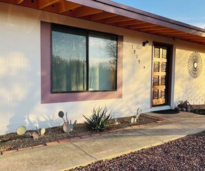 A modern house with a large window, a door with decorative panels, and a number '1919' on the wall. - Private Tucson Home with Fenced Yard (Tucson)