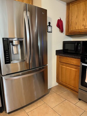 A stainless steel refrigerator with a water dispenser and a microwave on the countertop. - Private Tucson Home with Fenced Yard (Tucson)