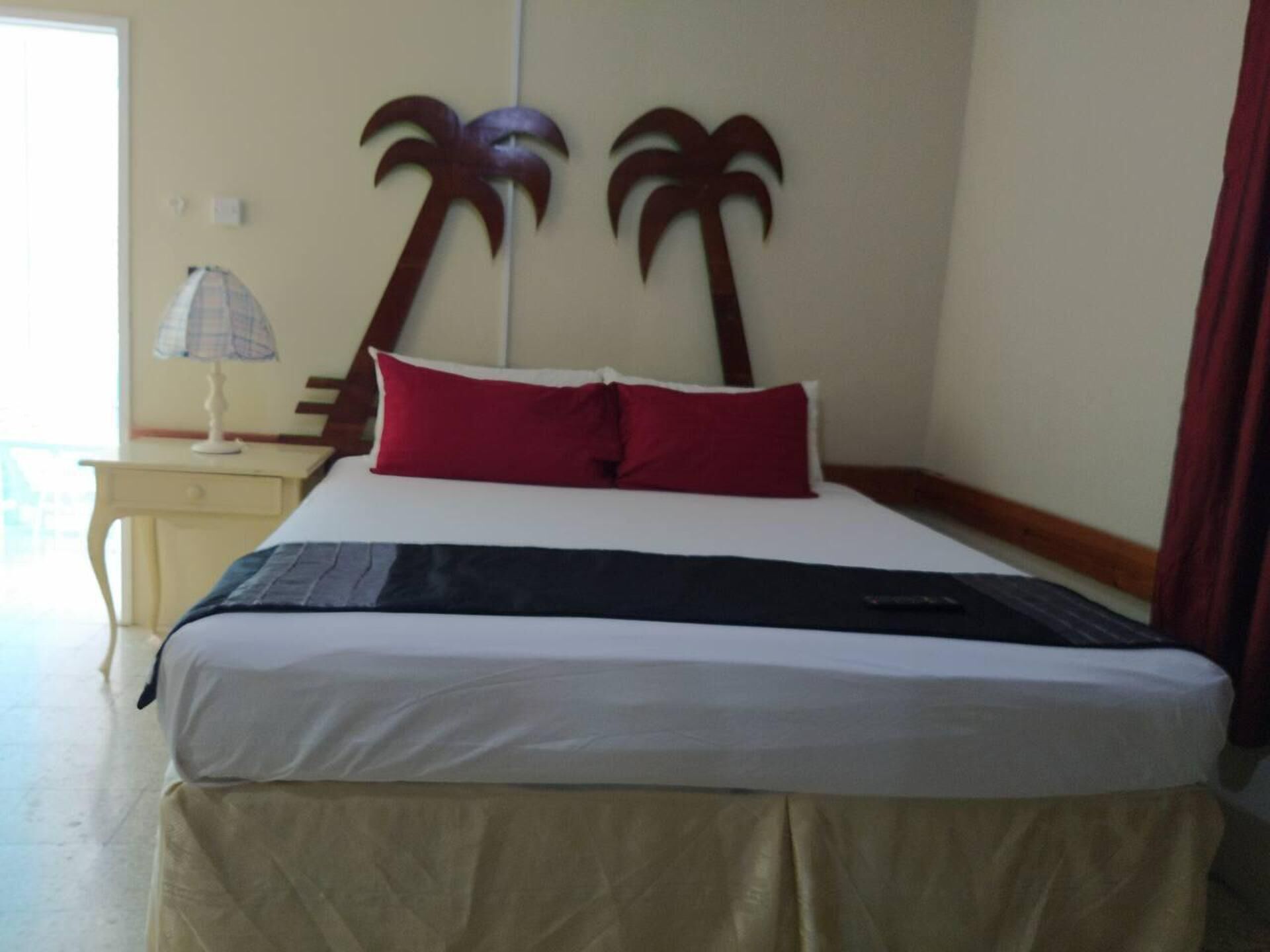 Ein Hotelzimmer mit Bett, Nachttisch, Lampe und Blick ins Freie.