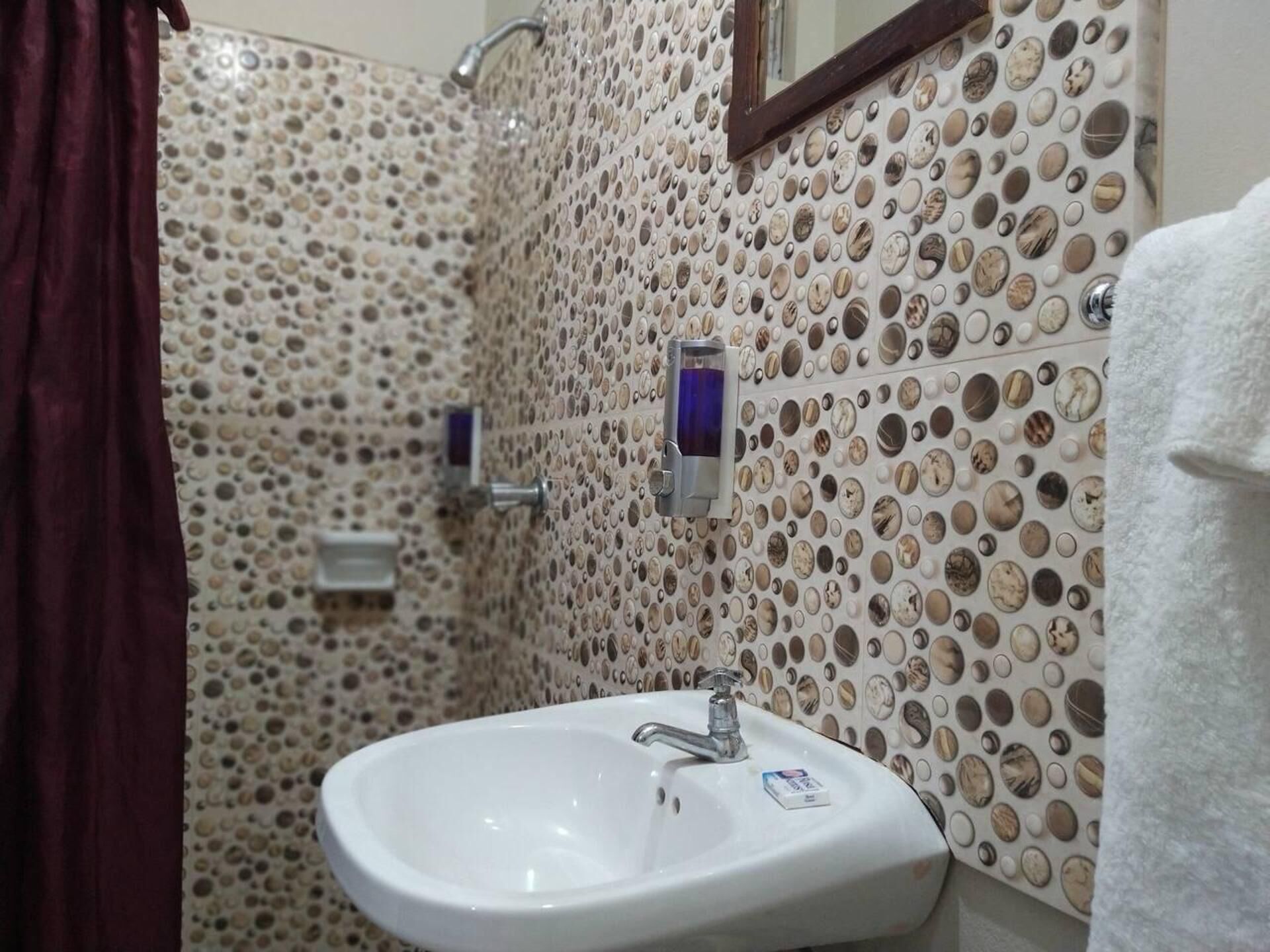 A bathroom with a sink, mirror, and shower area.