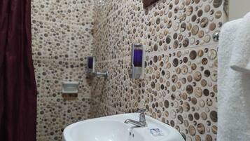 A bathroom with a sink, mirror, and shower area.