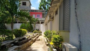 A narrow alleyway with a concrete path flanked by small plants and a wooden bench. - Tropical Haven in Discovery Bay - 6 Bedroom Villa (Discovery Bay)