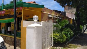 A yellow building with a green roof, a white fence, and a spherical object on top. - Tropical Haven in Discovery Bay - 6 Bedroom Villa (Discovery Bay)
