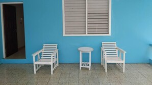 A room with blue walls, two white chairs, a small round table, and a window with blinds. - Tropical Haven in Discovery Bay - 6 Bedroom Villa (Discovery Bay)