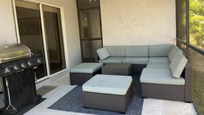 A covered patio with a grill, a sectional sofa, and a ceiling fan. - Pool Home next to Ritz and Vanderbilt beach (Naples)