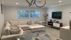 A modern living room with a sofa, coffee table, and dining area. - Pool Home next to Ritz and Vanderbilt beach (Naples)