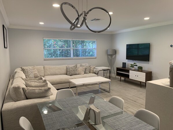 A modern living room with a sofa, coffee table, and dining area.