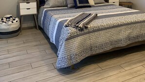 A bedroom with a large bed, a nightstand, a lamp, a window with blinds, and a framed picture on the wall. - Pool Home next to Ritz and Vanderbilt beach (Naples)