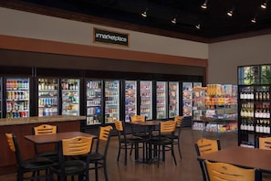 Guests can dine at tables and chairs in this marketplace area, offering a variety of beverages and food.