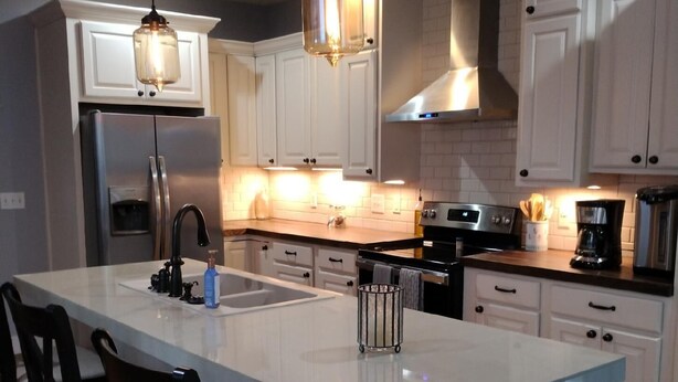 A modern kitchen with white cabinets, a large island with bar stools, stainless steel appliances, and pendant lighting. - Country Comfort and Views - 10 minutes from restaurants. (Newburgh)
