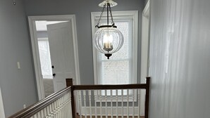 A multi-level interior with a wooden staircase, white railings, and a chandelier. - Country Comfort and Views - 10 minutes from restaurants. (Newburgh)
