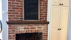 A brick fireplace with a welcome sign, wooden logs, and white cabinets. - Country Comfort and Views - 10 minutes from restaurants. (Newburgh)