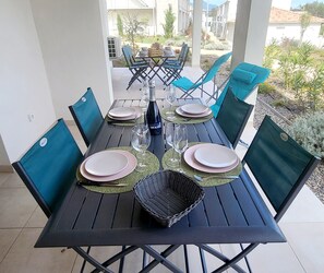 Une table à manger dressée pour quatre personnes, avec des chaises, une bouteille et des assiettes.