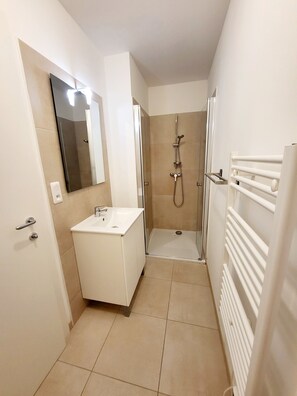 Une salle de bain moderne avec un meuble-lavabo blanc, une cabine de douche en verre et un radiateur blanc.