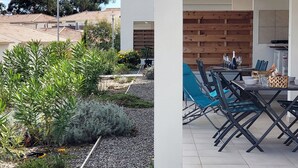 En udendørs patio med et spisebord dækket til to personer, omgivet af blå stole.