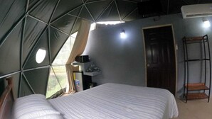 A tented accommodation room with a bed, a small desk with a computer, and a door. - Geodesic Dome 01, Jacuzzi with Hydromassage, 20 min from La Fortuna (Provincia de Alajuela)