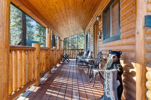 A wooden cabin with a covered porch, outdoor seating, and a bear statue.
