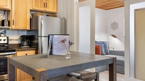 A modern kitchen with wooden cabinets, a stainless steel refrigerator, and a dining table with a vase. - Greer Cozy Cottage (Cabin 103) (Greer)