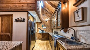 A kitchen with wooden flooring, granite countertops, a stainless steel sink, and wooden cabinets. - 4 Bedroom Rustic and Secluded Cabin. Dogs Welcome! (Empire)