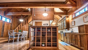 A wooden interior with a dining area, a tea display, and a kitchen with wooden cabinets. - 4 Bedroom Rustic and Secluded Cabin. Dogs Welcome! (Empire)