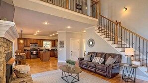 A spacious living area with a fireplace, a brown leather sofa, a coffee table, and a staircase leading to an upper level. - Lakehouse, Dock, Hot Tub & Tesla charger. Ideal for entertaining. Pet-Friendly! (Hiawassee)