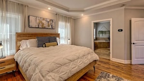 A bedroom with a large bed, wooden headboard, and a painting on the wall. - Lakehouse, Dock, Hot Tub & Tesla charger. Ideal for entertaining. Pet-Friendly! (Hiawassee)