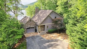 A house with a stone foundation, a grey roof, and a front porch. - Lakehouse, Dock, Hot Tub & Tesla charger. Ideal for entertaining. Pet-Friendly! (Hiawassee)