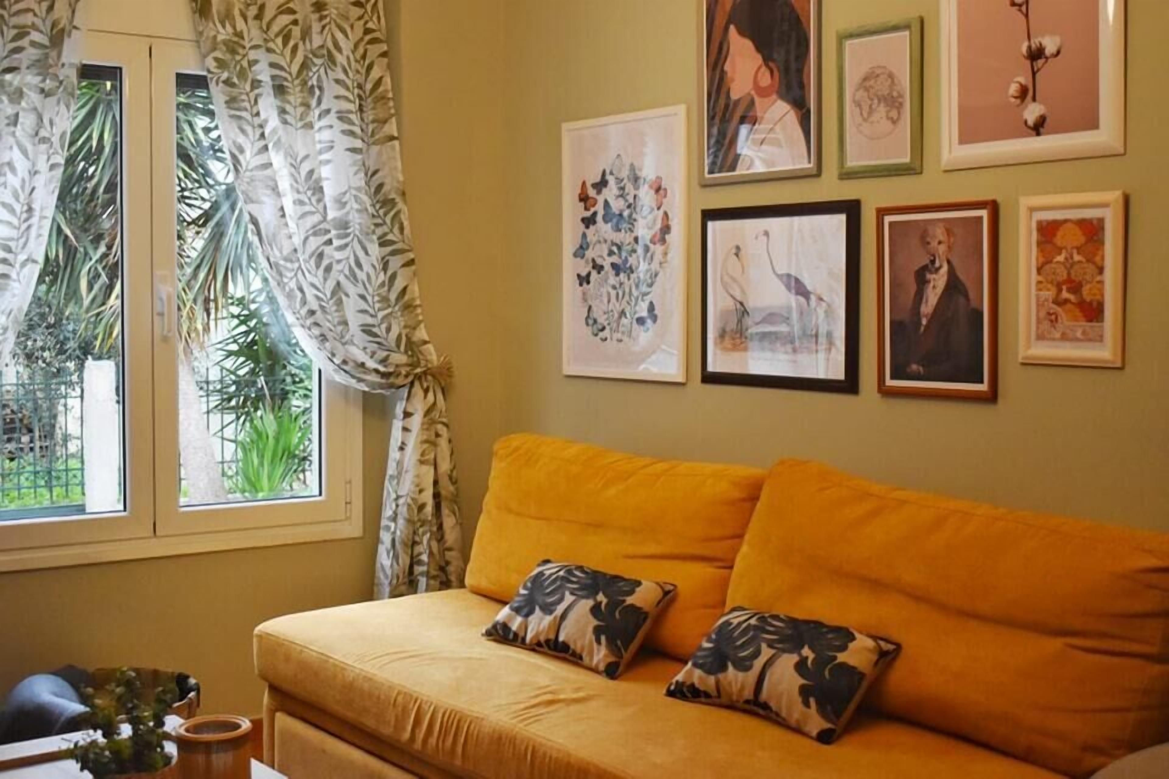 A living room with a sofa, floral cushions, and framed artwork on the wall.