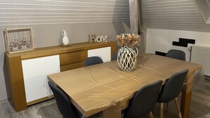 A dining area with a wooden table, black chairs, a white cabinet, and a decorative vase with dried plants. - Loft near Gerardmer (Corcieux)