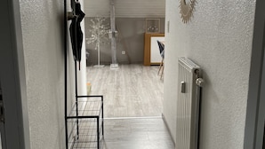 A hallway with a wooden floor, a radiator, a ceiling light fixture, and a door leading to a room. - Loft near Gerardmer (Corcieux)