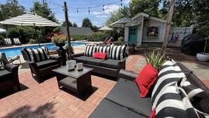 An outdoor patio area with wicker furniture, striped cushions, and a pool. - Downtown Hickory Lounge (Hickory)