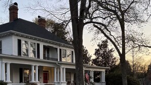 A two-story house with a porch, a flag, and a driveway. - Downtown Hickory Lounge (Hickory)