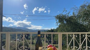 A bottle of Chardonnay and a bowl of fruit on a wooden table with a scenic mountain view in the background. - Relaxing peaceful retreat for 2 in a rural village in the Pyrenees (Rabouillet)