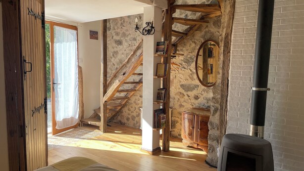 A rustic interior with a stone wall, wooden staircase, a fireplace, and a wooden door. - Relaxing peaceful retreat for 2 in a rural village in the Pyrenees (Rabouillet)