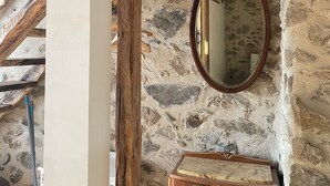 A rustic room with exposed stone walls, a wooden ceiling, a wooden cabinet, and a wall-mounted mirror. - Relaxing peaceful retreat for 2 in a rural village in the Pyrenees (Rabouillet)